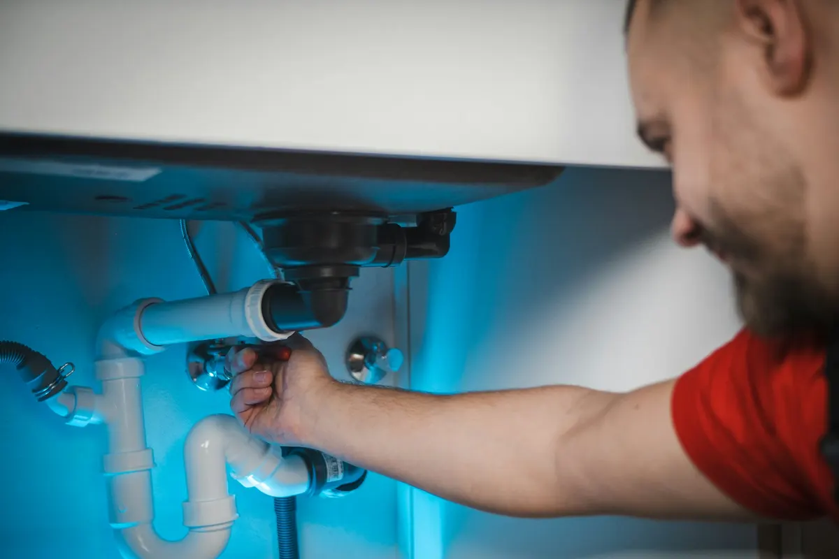 Plumber on his back under a sink, working on the drain pipe